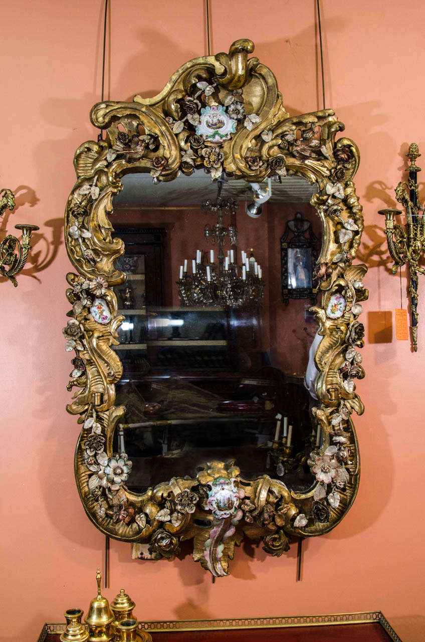 Un très beau et rare miroir Rococo en bois doré sculpté continental avec des montures en porcelaine.