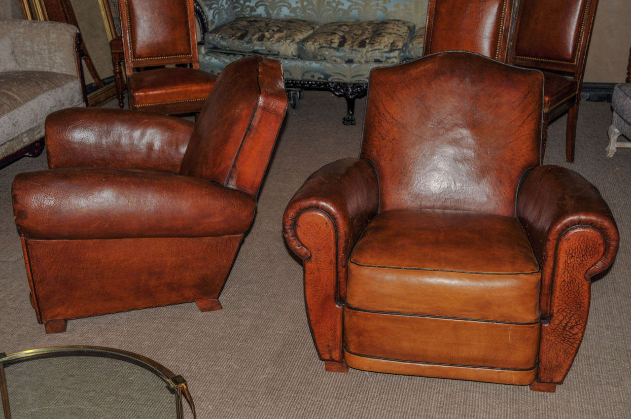 Pair of 1950's Club armchairs in tan leather and wood. Good condition. Normal wear consistent with age and use.