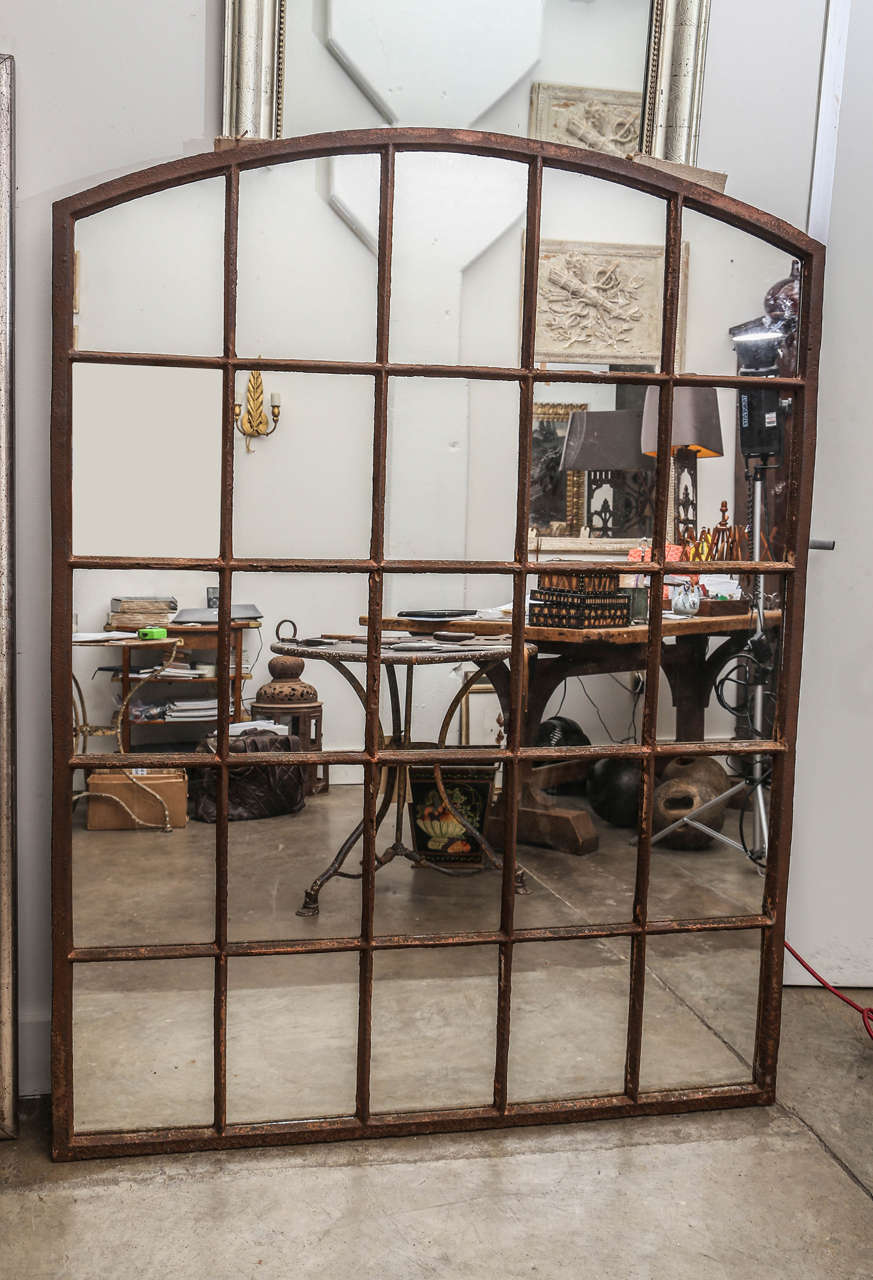 Eyebrow shape Industrial window made into a mirror from a linen warehouse in Belgium.