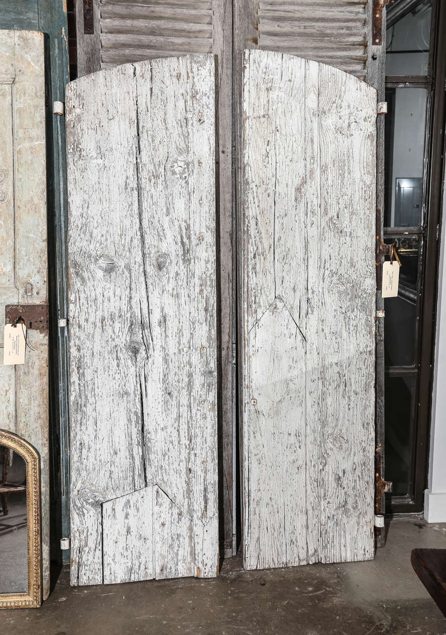 Pair of 18th century French shutters with original hardware scraped white paint. Wonderful weathered patina. The weathered look is from years of exposure to the elements. The shutters are sturdy. They would make wonderful doors. The left door has