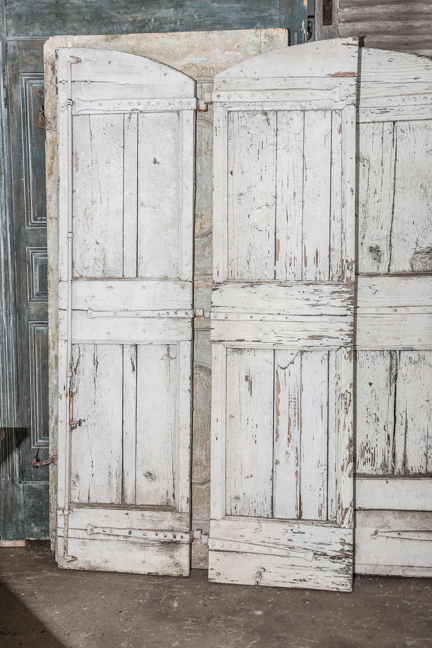 Pair of 18th C. French shutters with original hardware scraped white paint.  Wonderful weathered patina.  The weathered look is from years of exposure to the elements.  The shutters are sturdy.  They would make wonderful doors.