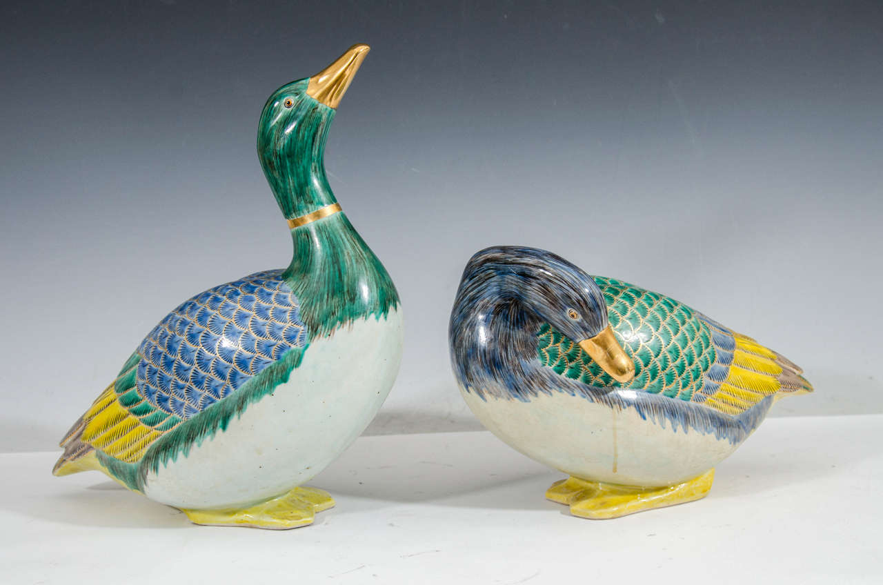 A vintage pair of highly decorative Asian inspired ceramic sculptural ducks with beautiful blue, green and yellow feathers and gilt accents. Good vintage condition with age appropriate wear. Some stress fractures due to age.

Bowed duck: 8
