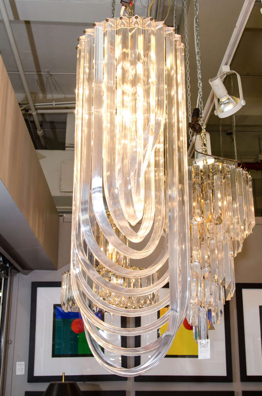 A vintage long chandelier, produced, circa 1970s with layers of looped Lucite, suspended from a brass frame and canopy. Very good condition, consistent with age and use.