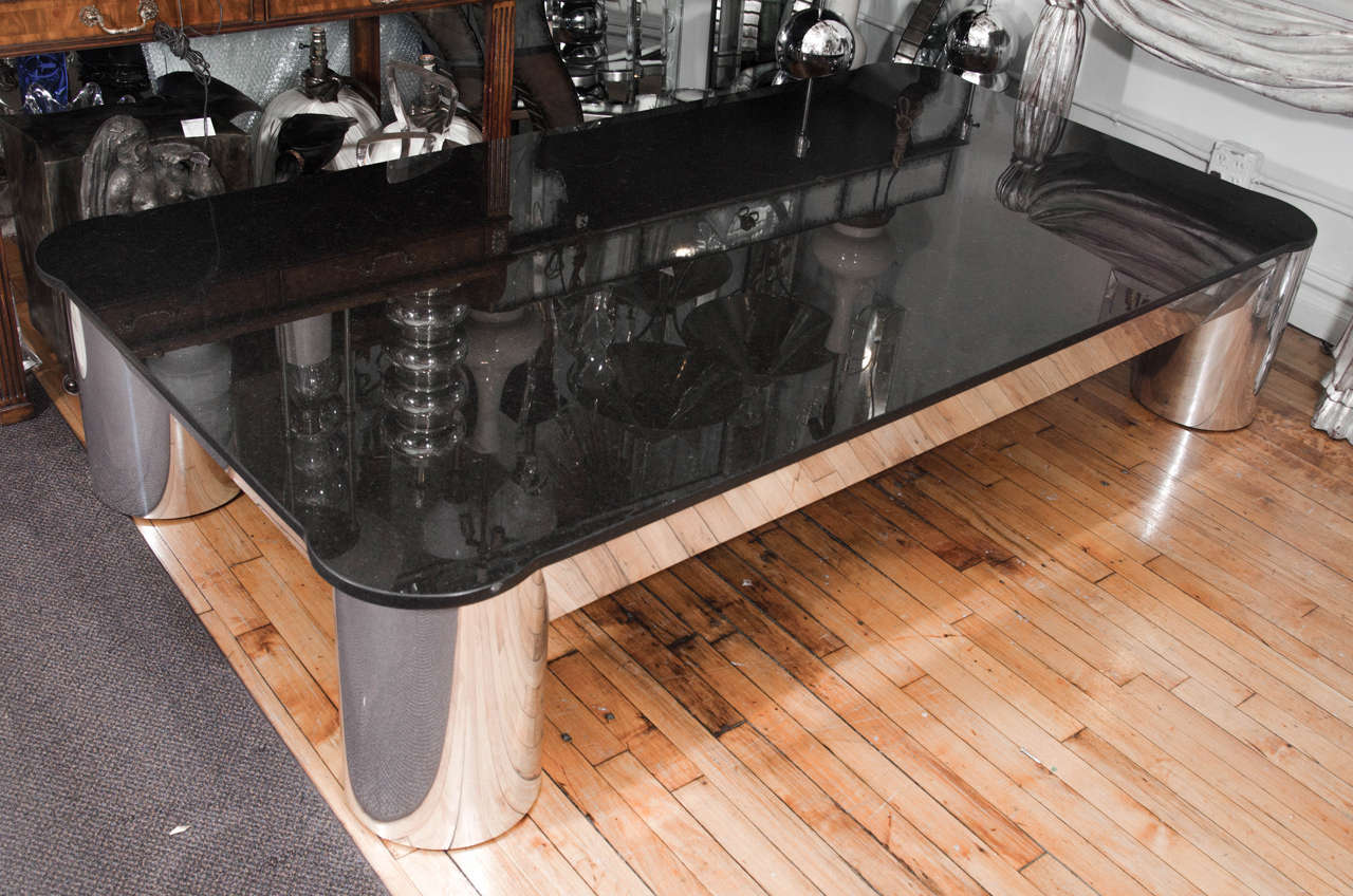 An oversized vintage coffee or cocktail table with black granite top and aluminum cylindrical legs.