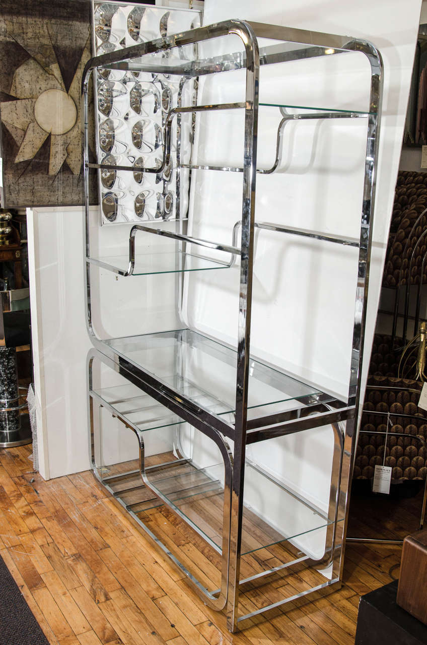 A vintage Milo Baughman chrome room divider or bookcase with glass shelves. The bottom section slides out to extend the width to 93.5. Good vintage condition with age appropriate wear and patina.