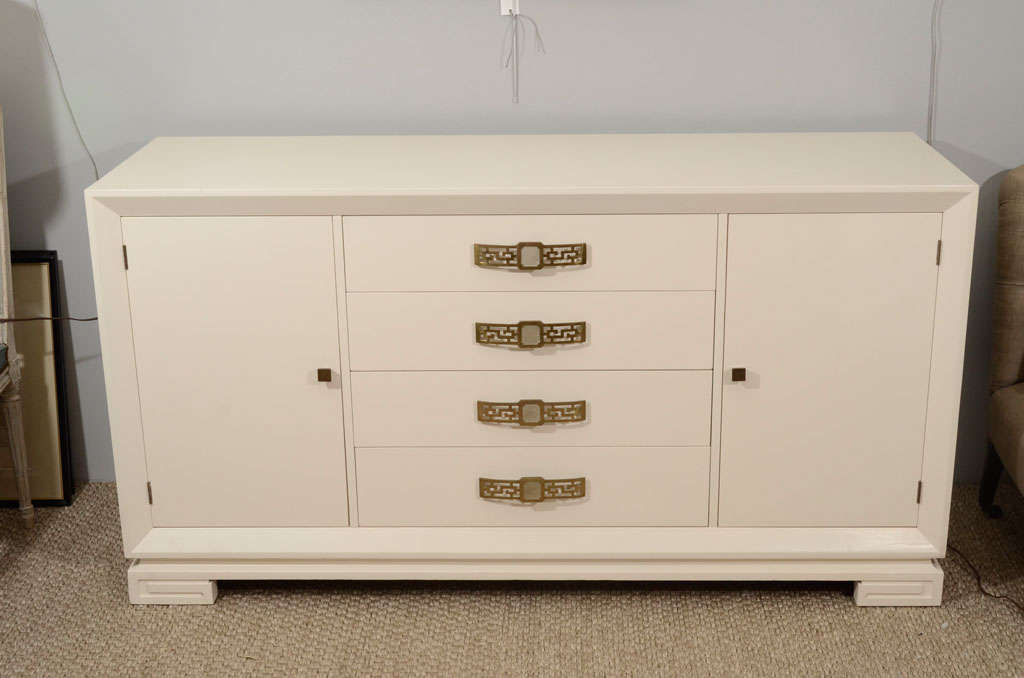A striking server in cream lacquer with original brass pulls, four drawers bordered by two cabinets for storage, with Greek key detail on feet. Perfect for a dining room or bedroom.
