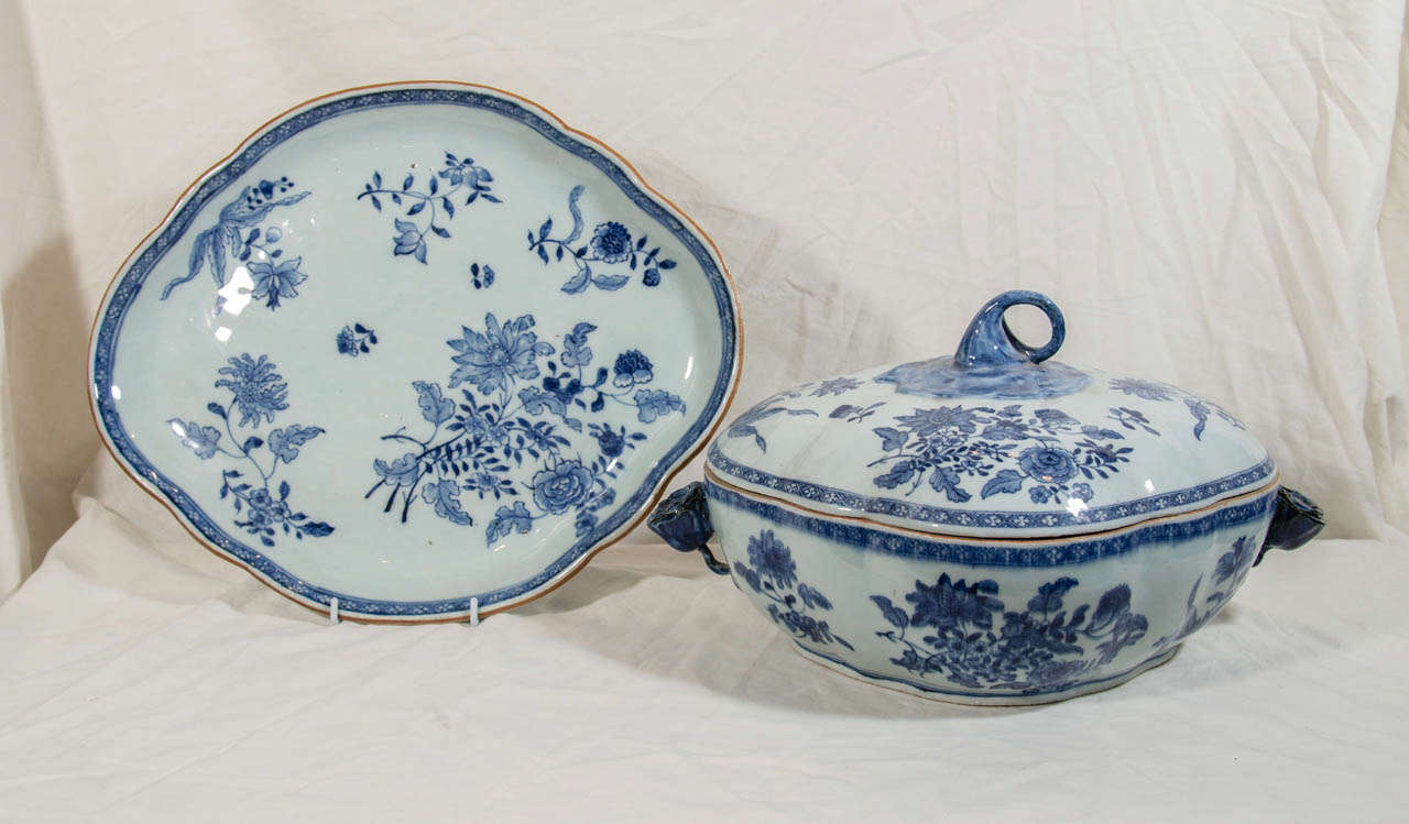 A fine Chinese export Blue and White covered soup tureen, and stand, Qianlong period (1736-95), made circa 1765. Painted with flower sprays the tureen has a lobed oval outline with a curled stem finial. The handles are in the form of  budding