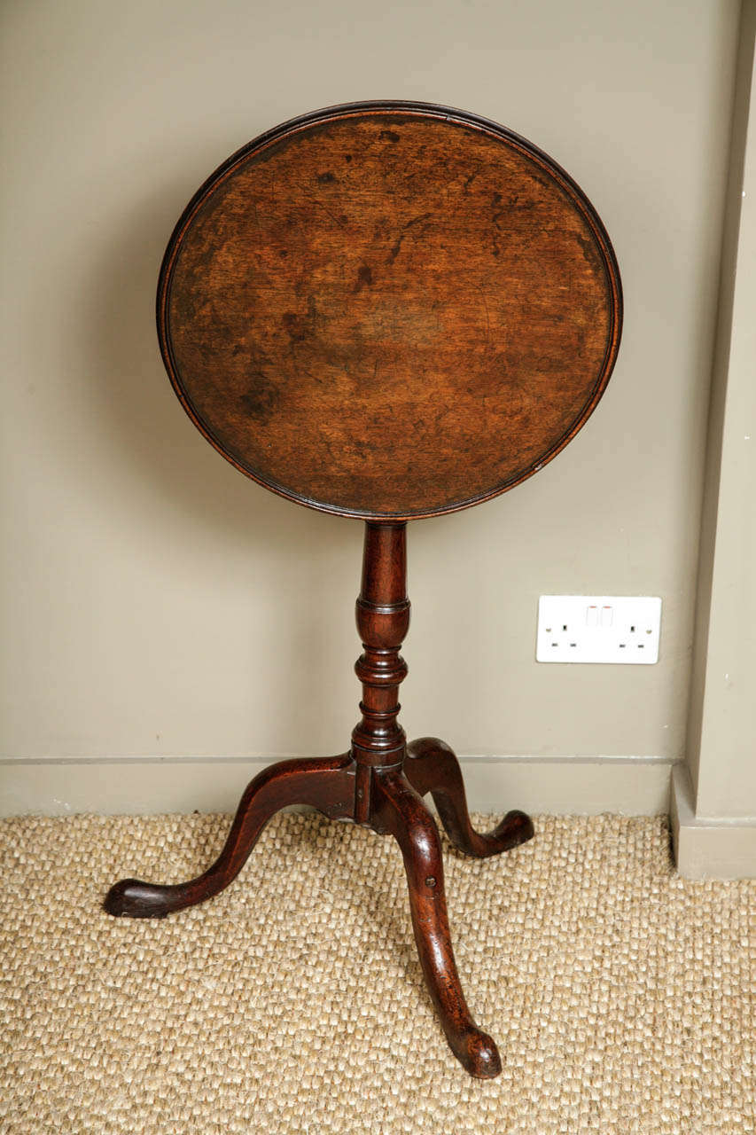 A small 18th Century fruit-wood tripod table with a well figured dish top with a good raised border. Somewhat provincial in manner, on a turned column with rings and vase. Terminating in cabriole legs on pad feet. Some old restorations to the legs