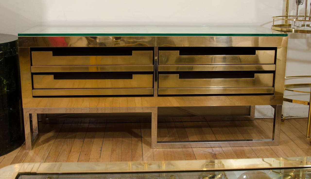 Rectangular brass low console with four storage drawers and chrome base.