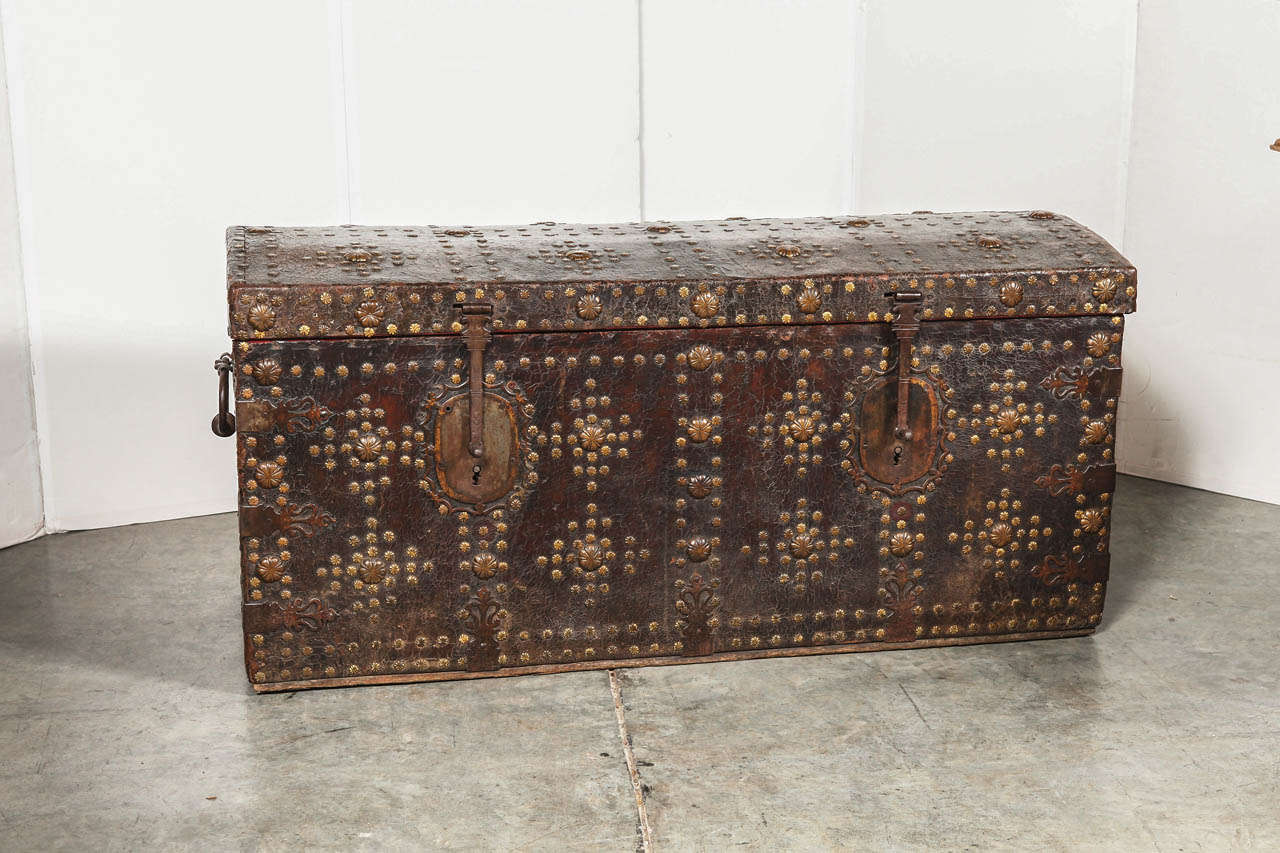 This fantastic French trunk from the 1600’s has been covered in leather on the front , sides and a portion of the wooden back which has been left in its raw state. The leather has been affixed to the wooden frame with intricately incised brass studs