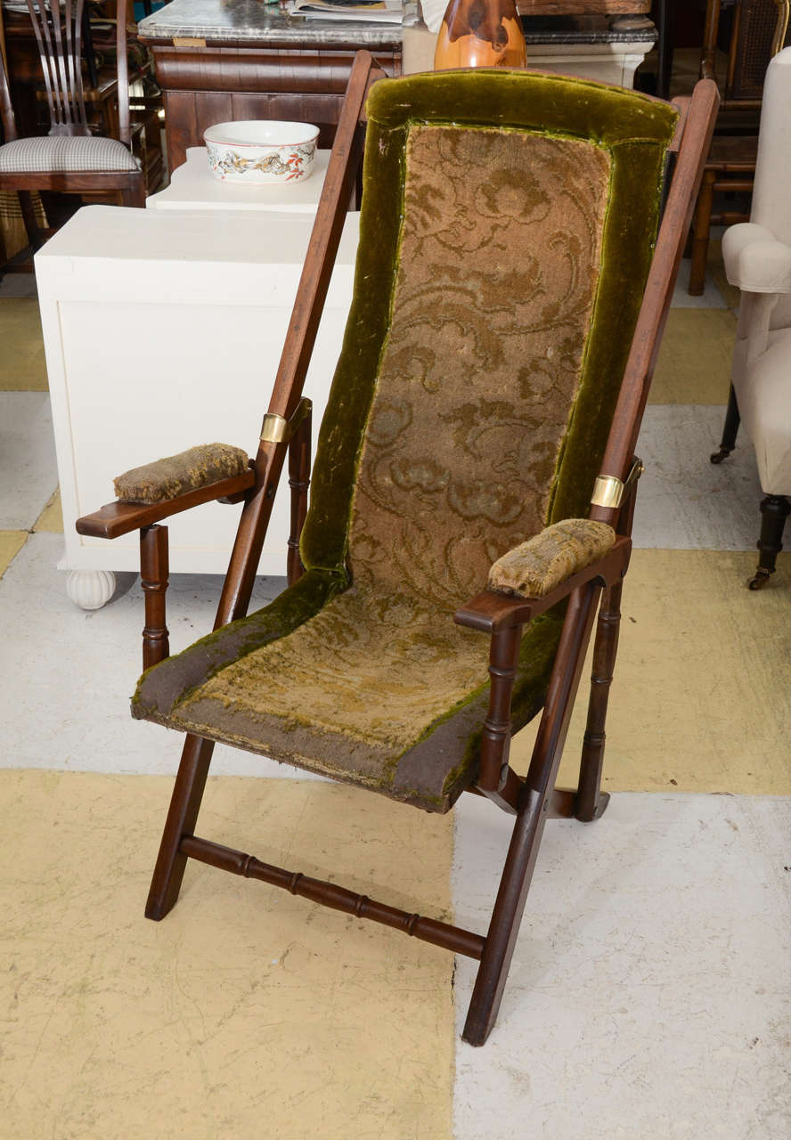 English FINE QUALITY WALNUT UPHOLSTERED FOLDING CAMPAIGN CHAIR. BACK FRAME CONTOURED TO THE SHAPE OF THE BACK ; MAKING IT VERY COMFORTABLE.  THE FRAME IS JOINED BY TURNED BACK SUPPORTS & STRETCHERS. THE FRAME IS LOCKED IN PLACE WITH DECORATIVE BRASS
