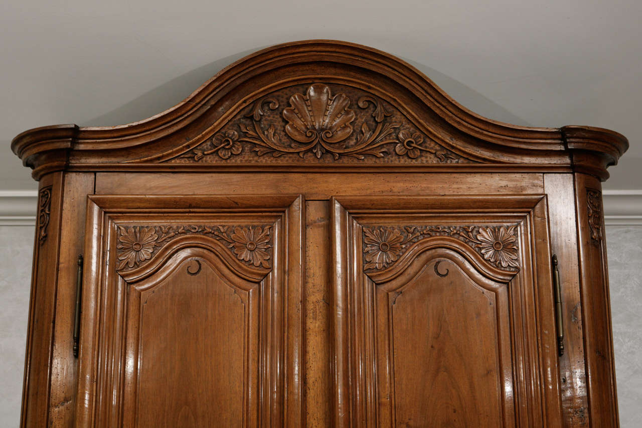 18e s. Cabinet en deux parties en noyer français de la période Régence.  Le meuble est très finement sculpté et présente un motif de coquillage.
