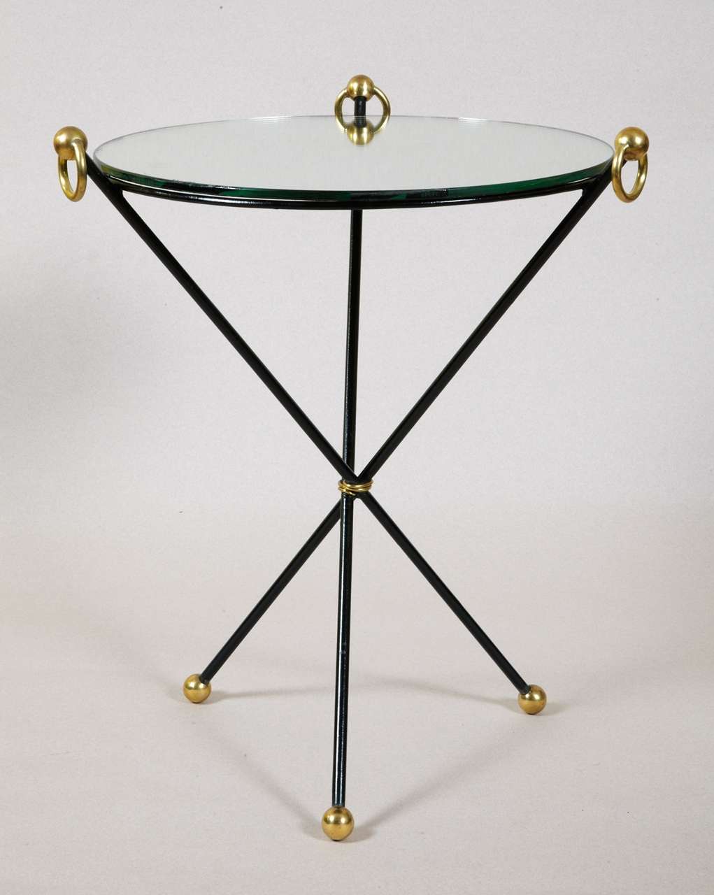 Elégante table d'appoint  1940 , en fer forgé, pieds se terminant par par boule en laiton. Plateau d'origine amovible en miroir souligné par trois anneaux en laiton