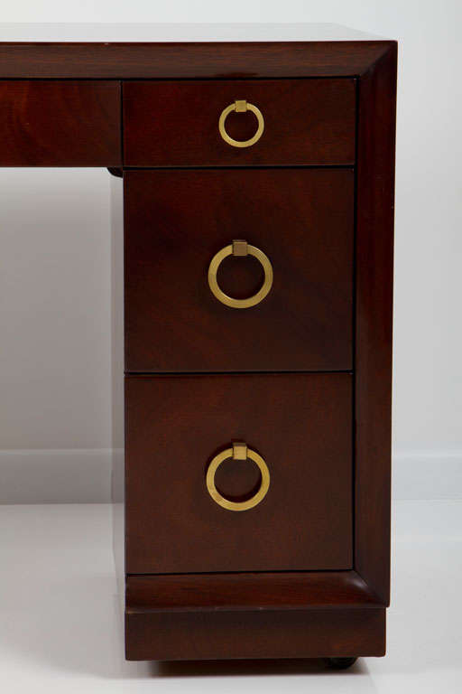 A classic kneehole desk with round brass door knocker drawer pulls, three drawers in each pedestal and a center drawer located under the top surface, mod. no. 317, by T.H. Robsjohn-Gibbings and produced by Widdicomb. American, circa