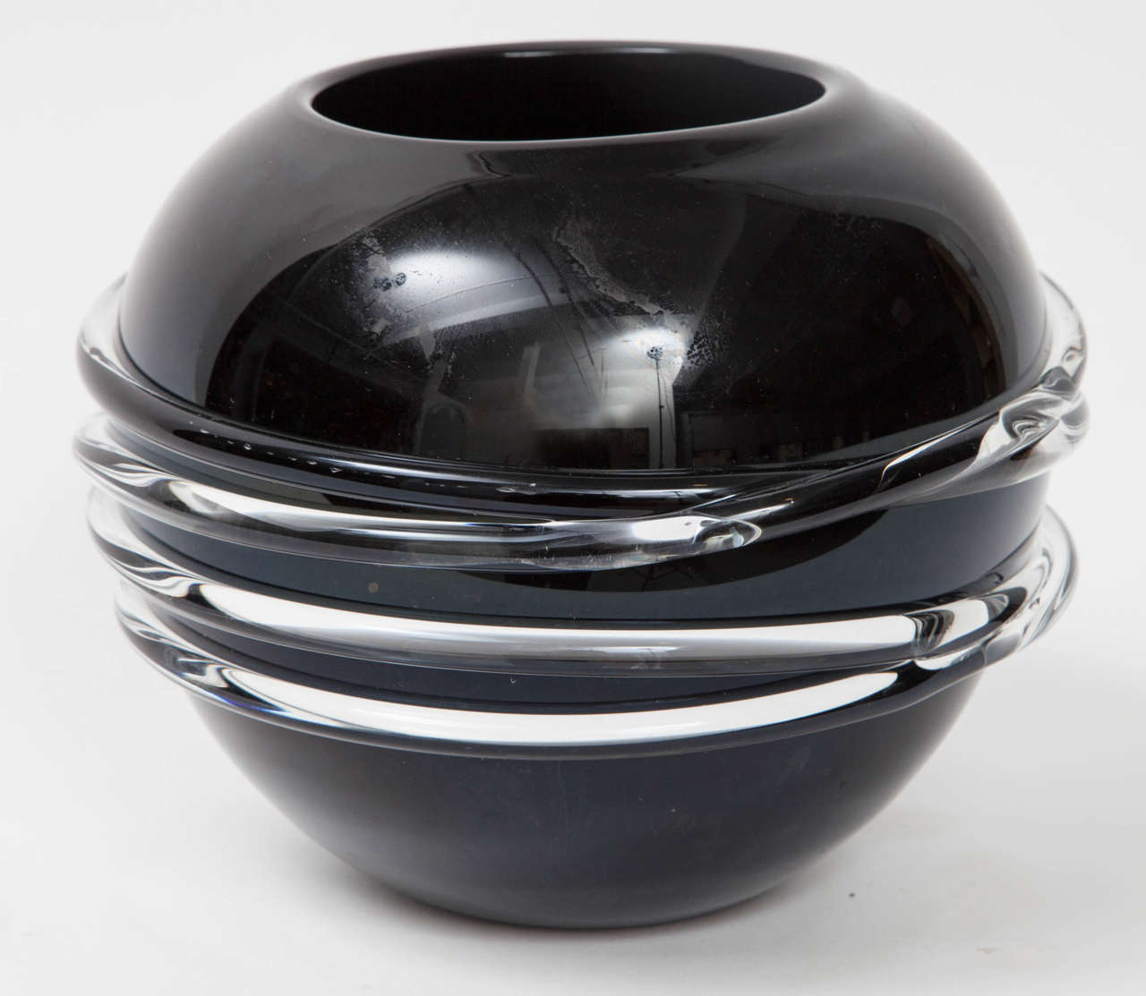 A dramatic black glass spherical vase, Italy, circa 1960. Made of black glass with clear glass banded accents. Unsigned.