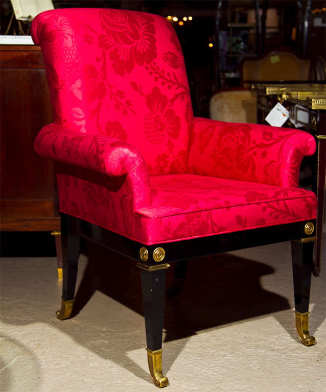 Pair of glamorous Regency style armchairs, circa 1940s, rolled back and arms, upholstered in red fabric, supported by ebonized legs ending in bronze sabots.