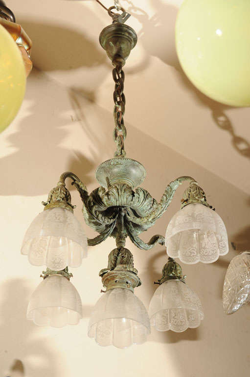 We have a matched pair of these elegant five arm chandeliers.  They are patinated in a verde gris finish and have five period, deep-etched glass shades on each.  All are matching.  You may buy one or both.