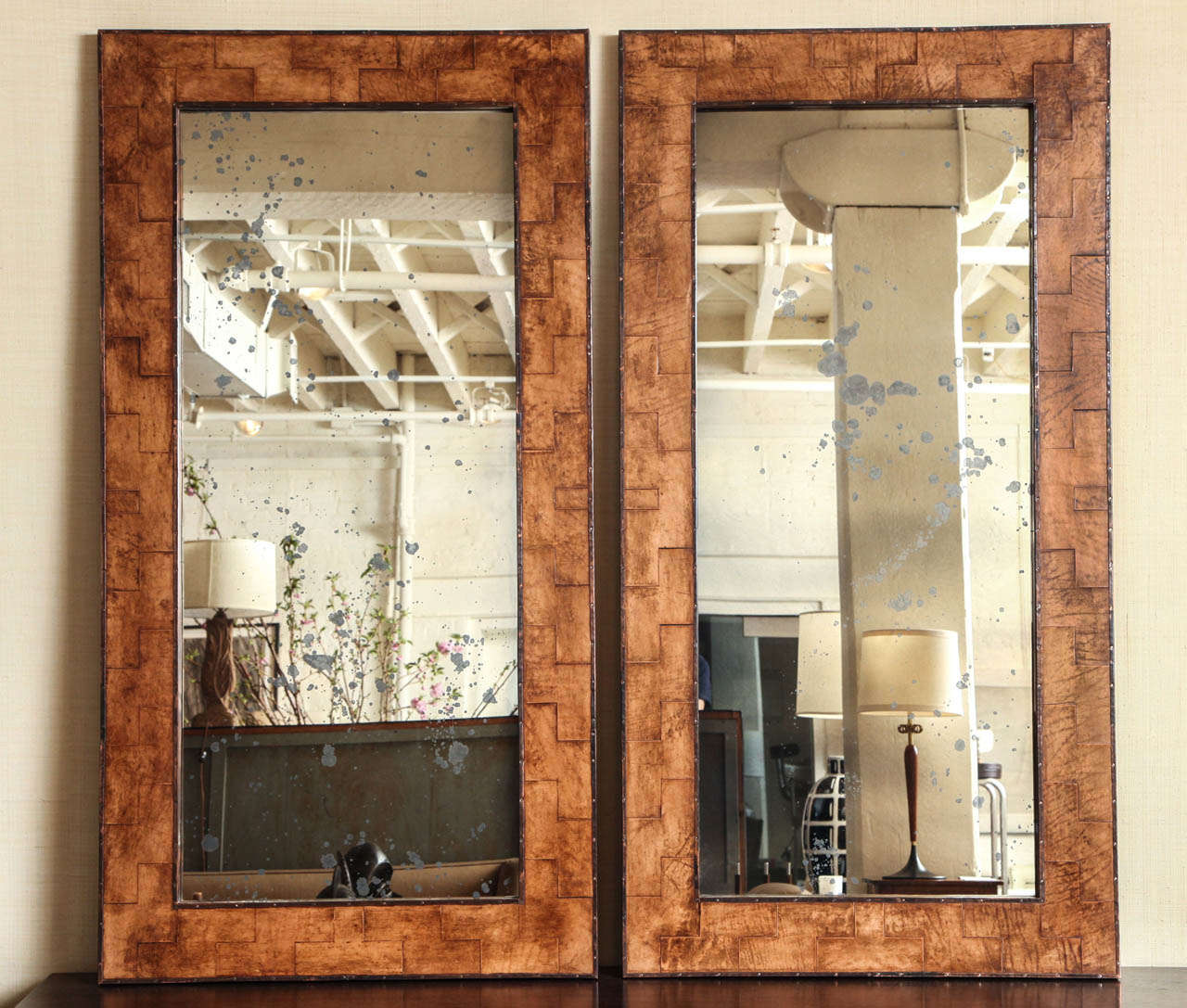 Pair of tall mirrors with frames that are made from vintage leather and metal molding. The mirror has beautifully antiqued glass.