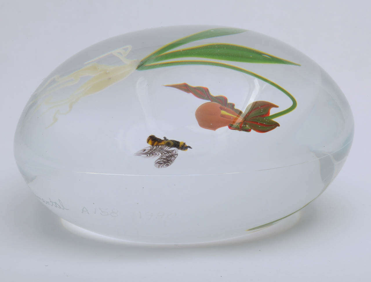 An early Paul; Stankard orchid and bee paperweight with an orange and green orchid and hovering bee, signed S for Stankard, Experimental, 1980