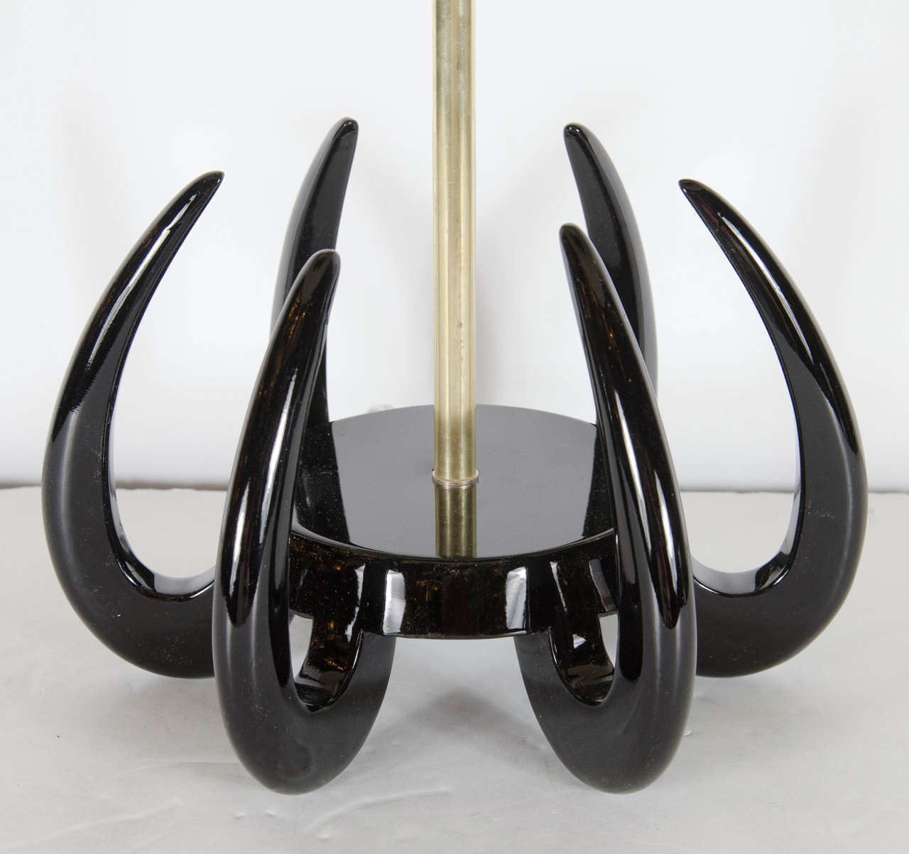 With their refined materials and clean lines, this elegant pair of Mid-Century Modernist sculptural table lamps represents exceptional examples of Mid-Century design. They feature an ebonized walnut saber base consisting of six curved arm extending