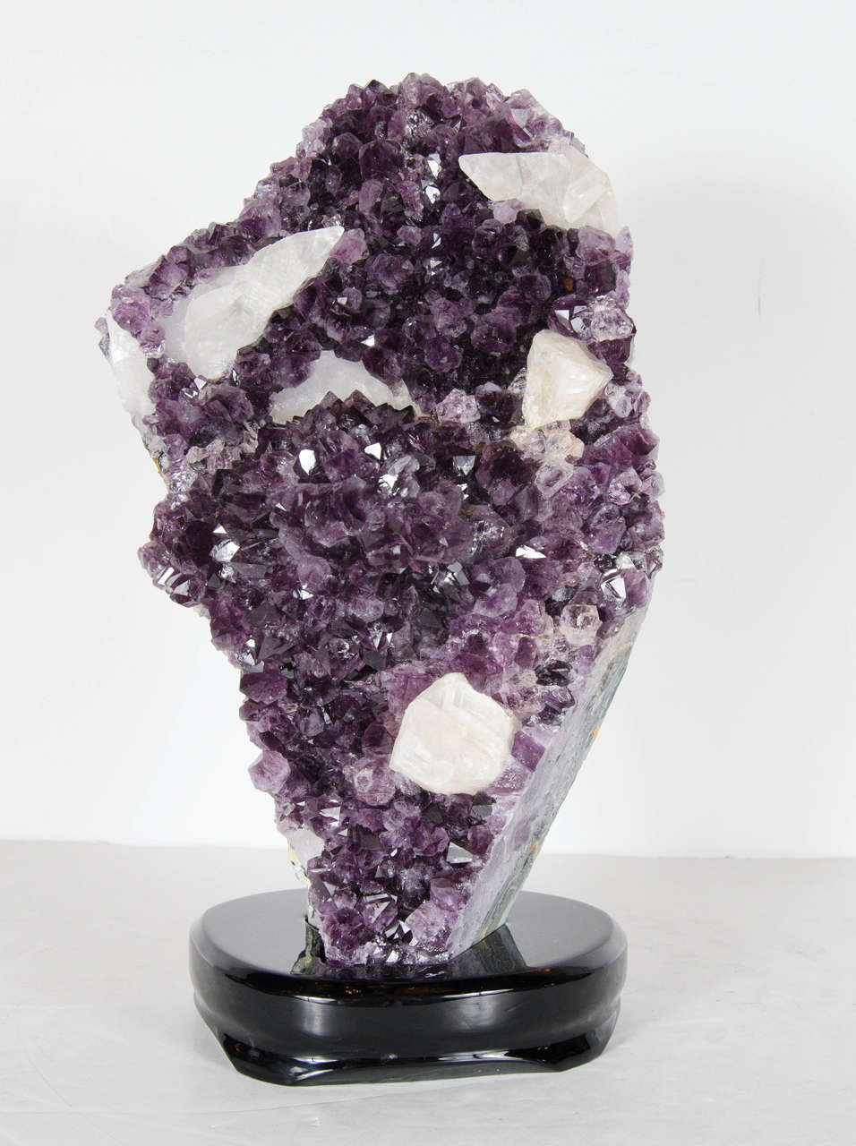 This majestic rock specimen features vibrant and rich Amethyst and with inset White Quartz specimens as well. It is a one of kind and rests on an ebonized walnut base. This geode would look luxurious in any room or decor.