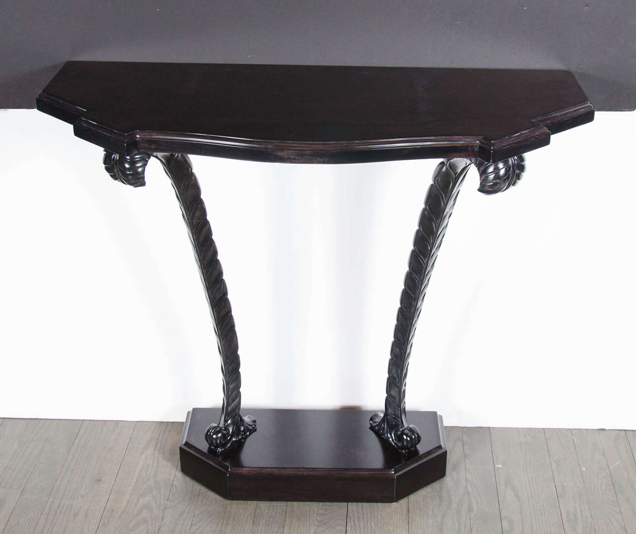 1940s Hollywood Regency plume console table by Grosfeld House in ebonized walnut. This elegant console table by Grosfeld House has a pedestal base with a stepped top design. The top of the console mimics the tables base but with more fluidity in its