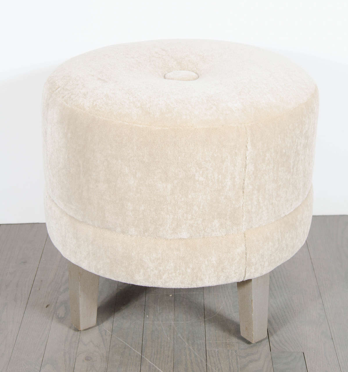Art Deco round stool newly upholstered in camel mohair with a large button detail on the top seat. This stools height is accentuated with its overall tall design and the features an upholstered band that runs along the bottom acting as trim. It sits