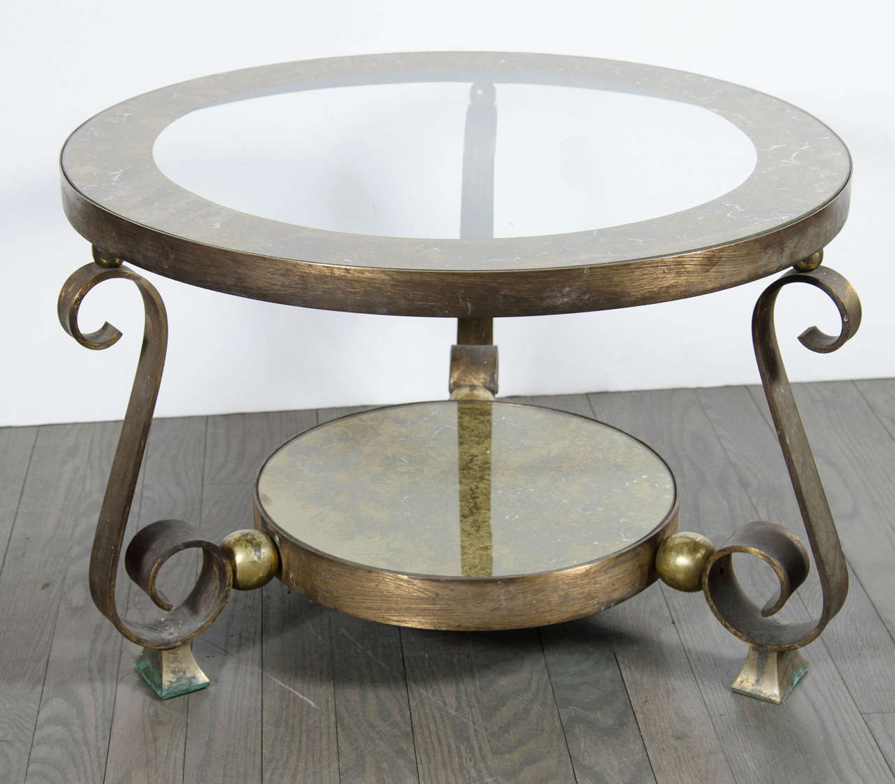 This gorgeous  occasional table by Arturo Pani is an exceptional piece. This table is designed in patined bronze, brass, and has gorgeous reverse eglomise detailing in a bronze and gold finish. The legs feature a stylized scroll form design  with