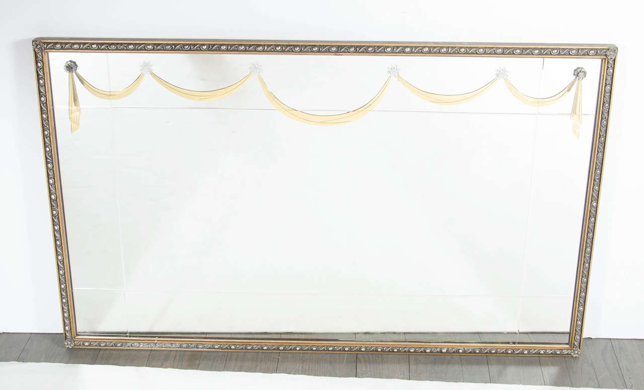 This elegant 1940s Hollywood gilt mirror was realized in the United States by the esteemed maker Grosfeld House, circa 1945. It features a Lucite drape design with reverse etched detailing surrounded by a 24-karat yellow gold leaf frame. With its