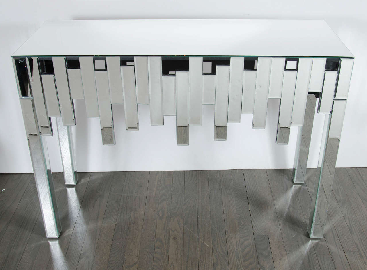 Mid-Century Modernist mirrored Skyscraper style console table.  This streamline console table features a beveled mirrored top that sits atop an array of multi-faceted individually beveled mirrored pieces that are attached in a staggered formation
