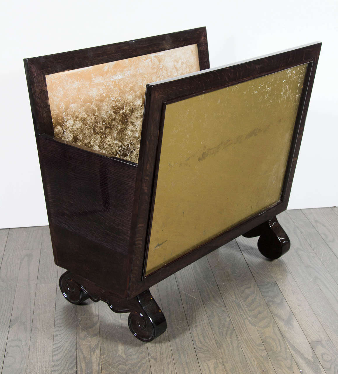 This unique Mid-Century Modernist reverse pained ebonized walnut log holder features two elongated side panels set an angle of reversed painted glass in mottled gold on the insides. These reverse painted panels are framed within ebonized walnut
