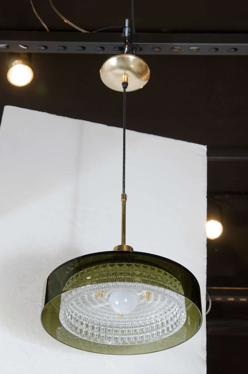 This gorgeous Mid-Century modernist pendant by Carl Fagerlund for Orrefors is exceptional. It features an outer stylized dome in handblown smoked grey glass with an inner dome of textured glass. It has brass detailing and fittings. It is in