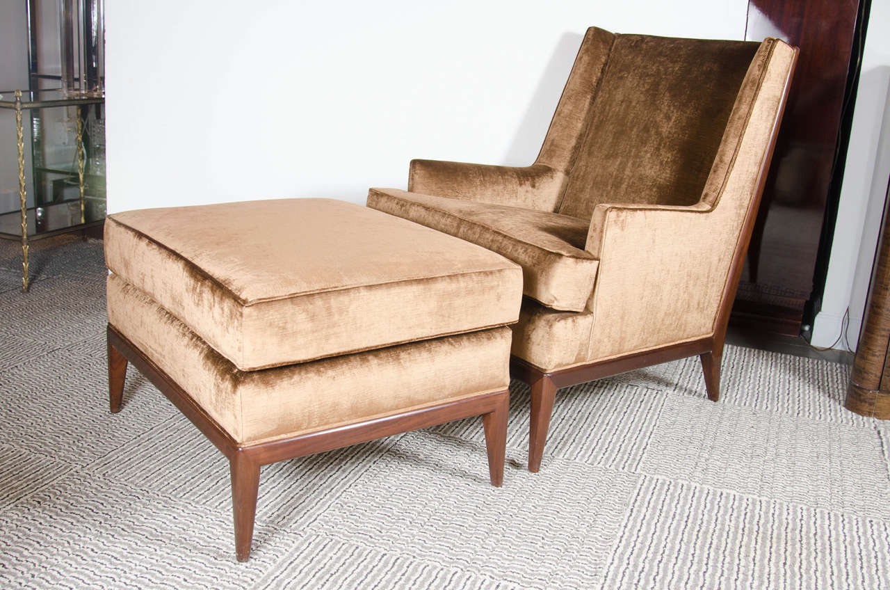 This very chic Mid-Century Modernist chair/ottoman in the manner of Dunbar is stunning. It has a beautiful silhouette, sumptuous tobacco velvet upholstery, and  tapered walnut legs and frame detailing .It has been newly upholstered and restored and