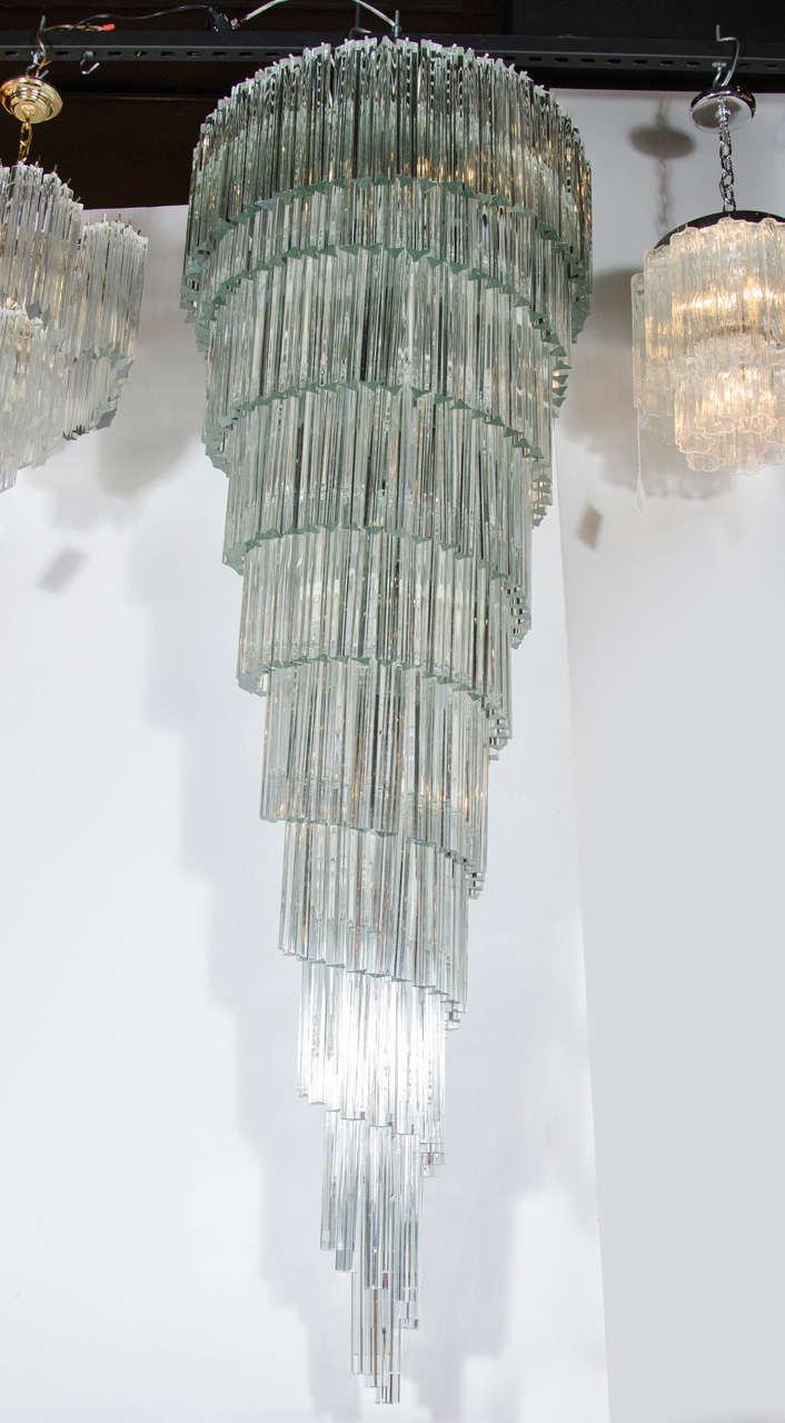 This monumental Italian chandelier features clear Murano hand blown glass rods that cascade from the upper layer into a spiral design. It has 25 edison base bulbs and has been newly rewired to American standards. This chandelier will add a real