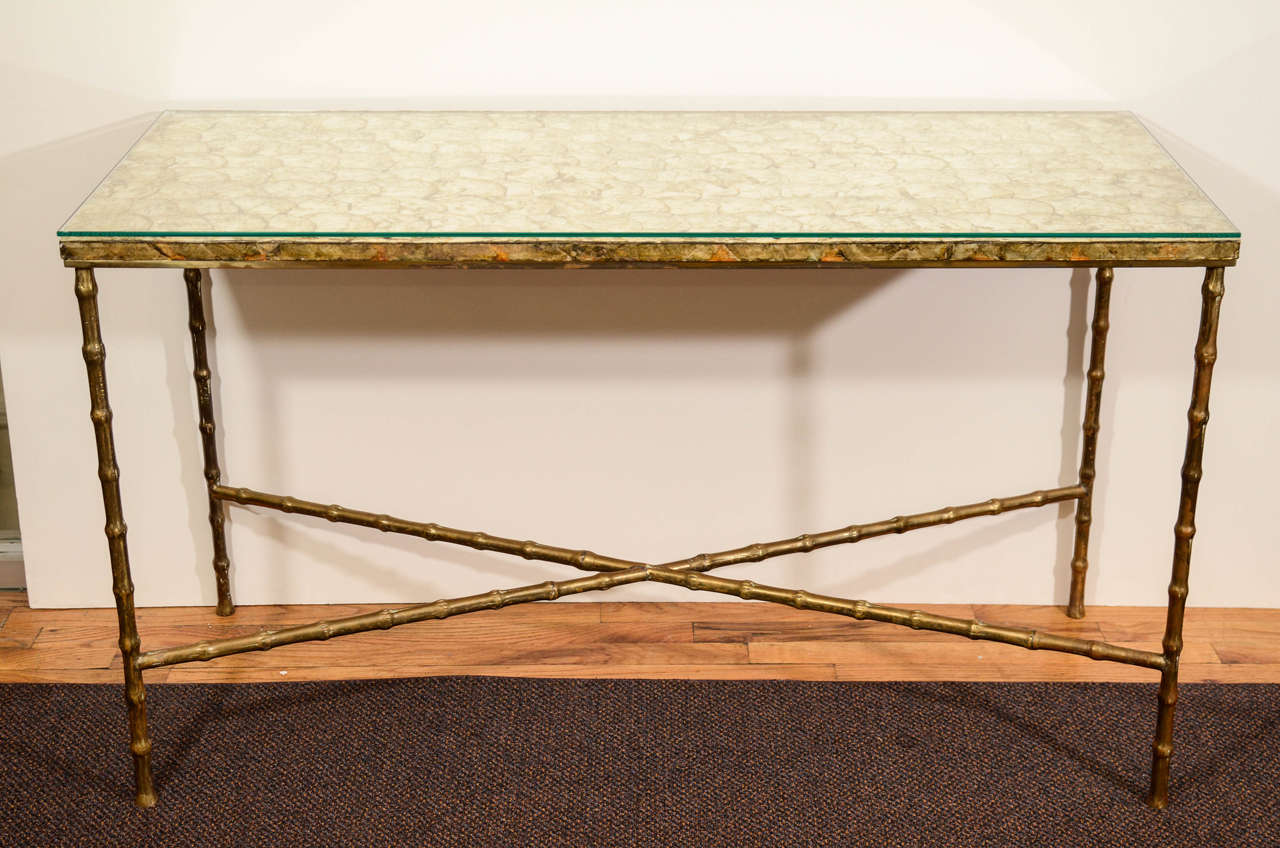 A vintage French console table, produced circa 1950s in the style of Maison Baguès, with a capiz shell surface under glass, above a brass faux bamboo frame, with cross stretcher. Good vintage condition with age appropriate wear and some scratches.