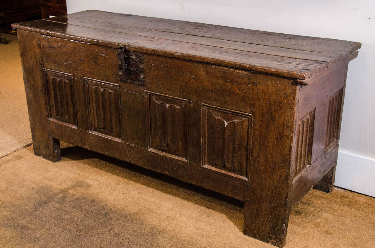 Of plank construction, the rectangular hinged-top above carved linen-fold panelled front and sides, the open interior with a small side hinged-compartment, with original metal lock. c. 1480