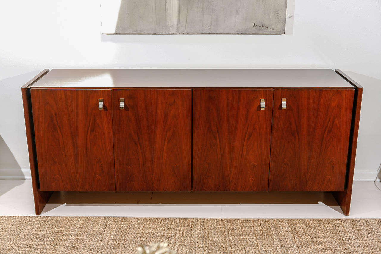 A four-door rosewood credenza with ample amount of storage space and original chrome pulls, this piece offers the duality of serving as a sideboard or a credenza. The rosewood grain is truly beautiful, deep and rich.