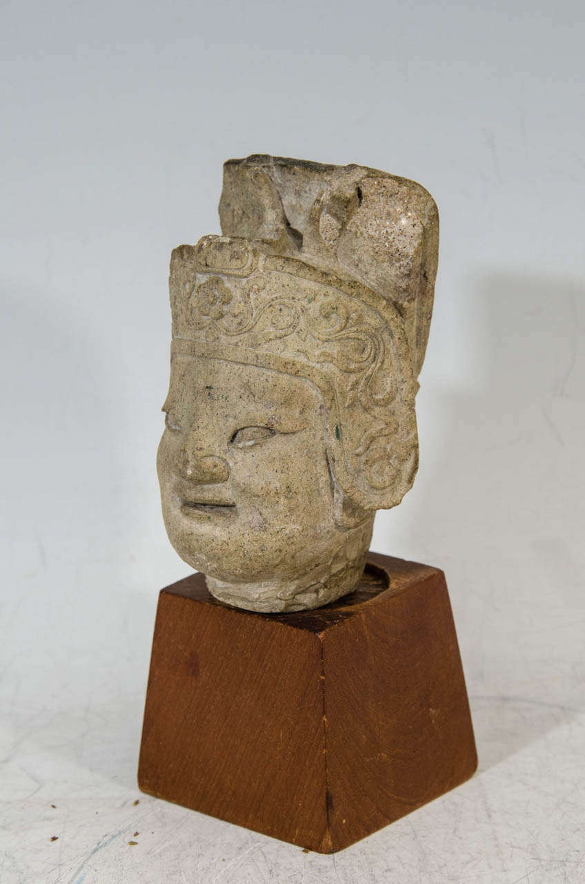 A Ming Dynasty finely carved stone head of a Warrior General (possibly the protector, Guandi).  The elaborate headdress has scrolling flowers, and it is mounted on a modern hardwood base

Fair condition with age appropriate wear as this is an