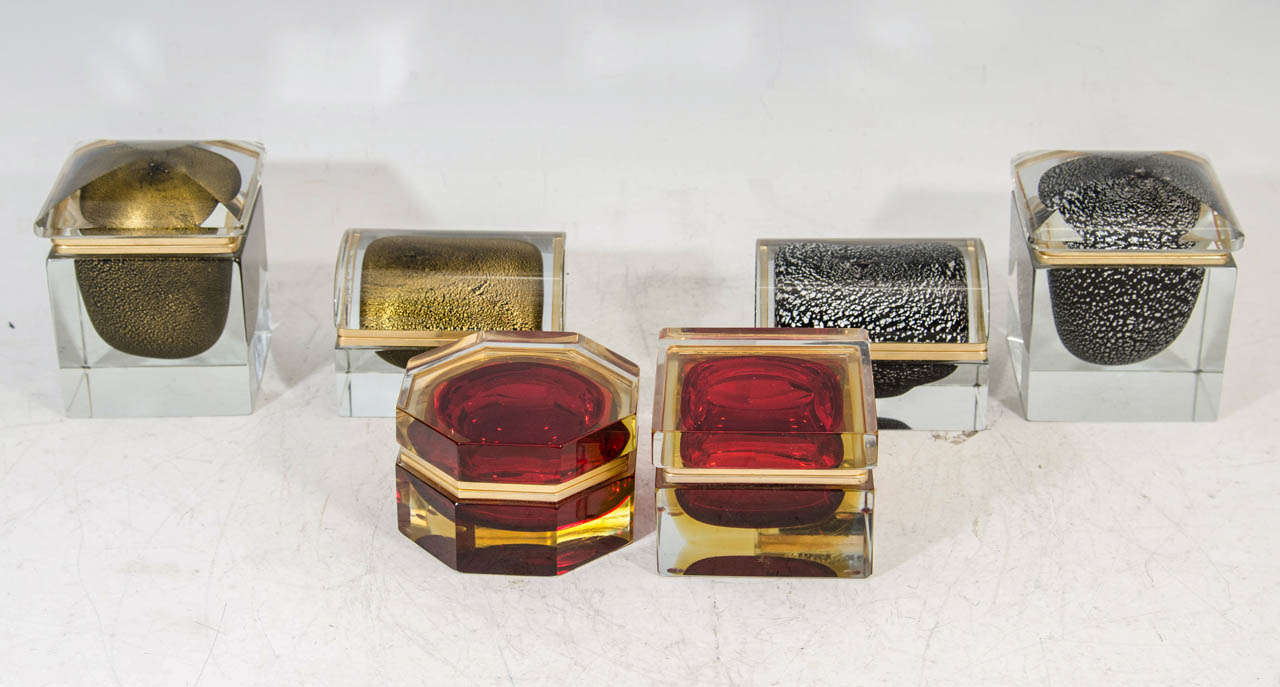 A vintage set of six Cenedese Murano glass heavy boxes in various shapes and colors.  All have brass trim and hinges.  There is a gold rectangular and square box.  There is a red and gold octagonal and square box, and there is black rectangular and