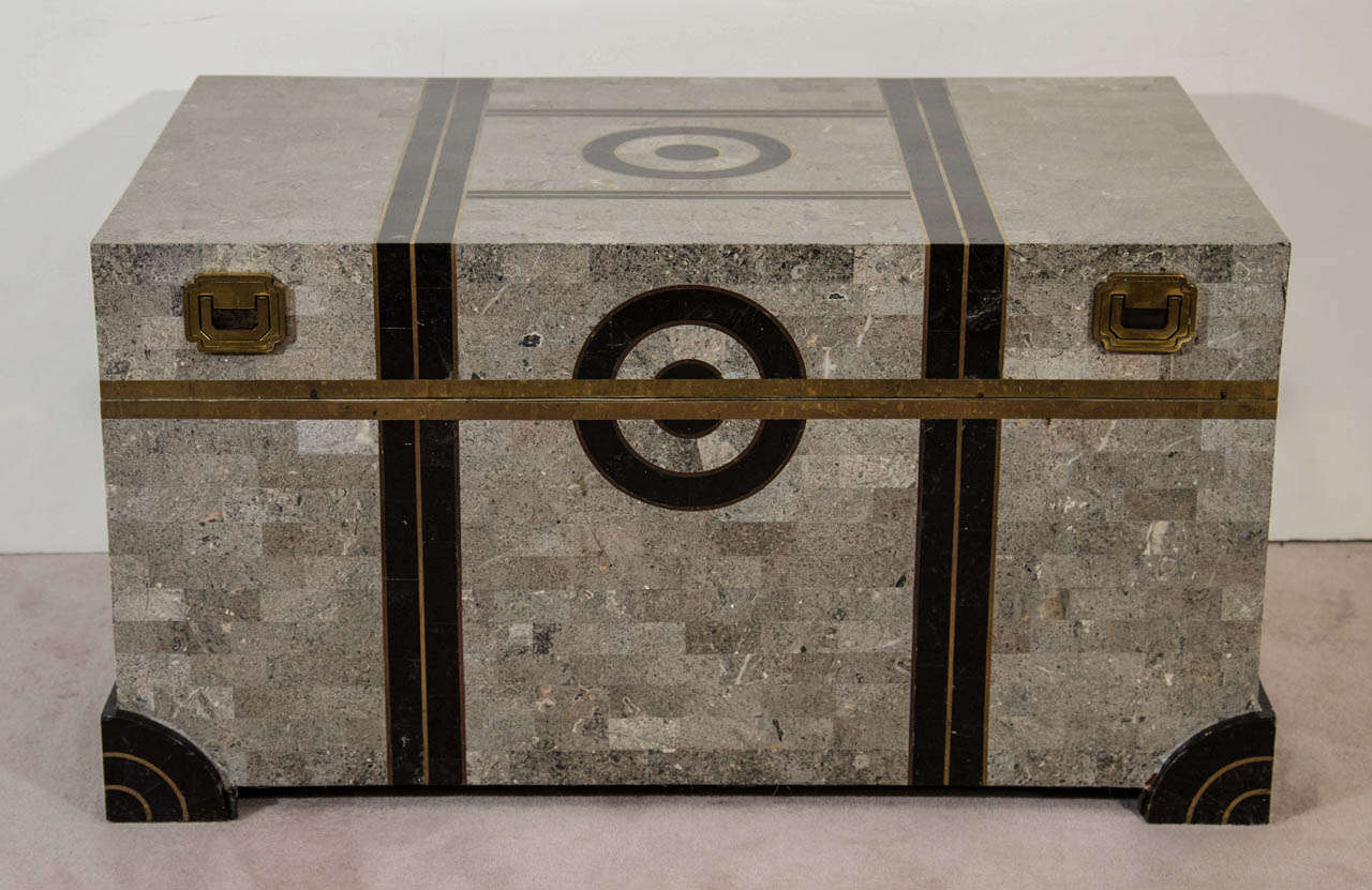 A tessellated stone trunk, produced circa 1980s by Robert Marcius for Casa Bique, with black stone detail, and brass inlay and pulls. This piece remains in good condition, with age appropriate wear.