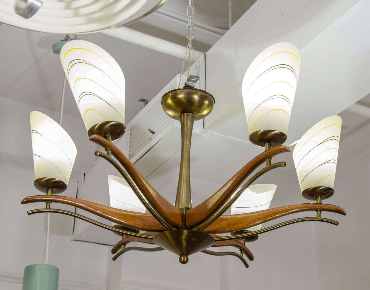A vintage Italian chandelier with wooden arms accented by parallel brass elements. Central stem is brass. Slanted oval glass shades feature delicate gold and black detailing. Good vintage condition with age appropriate wear.