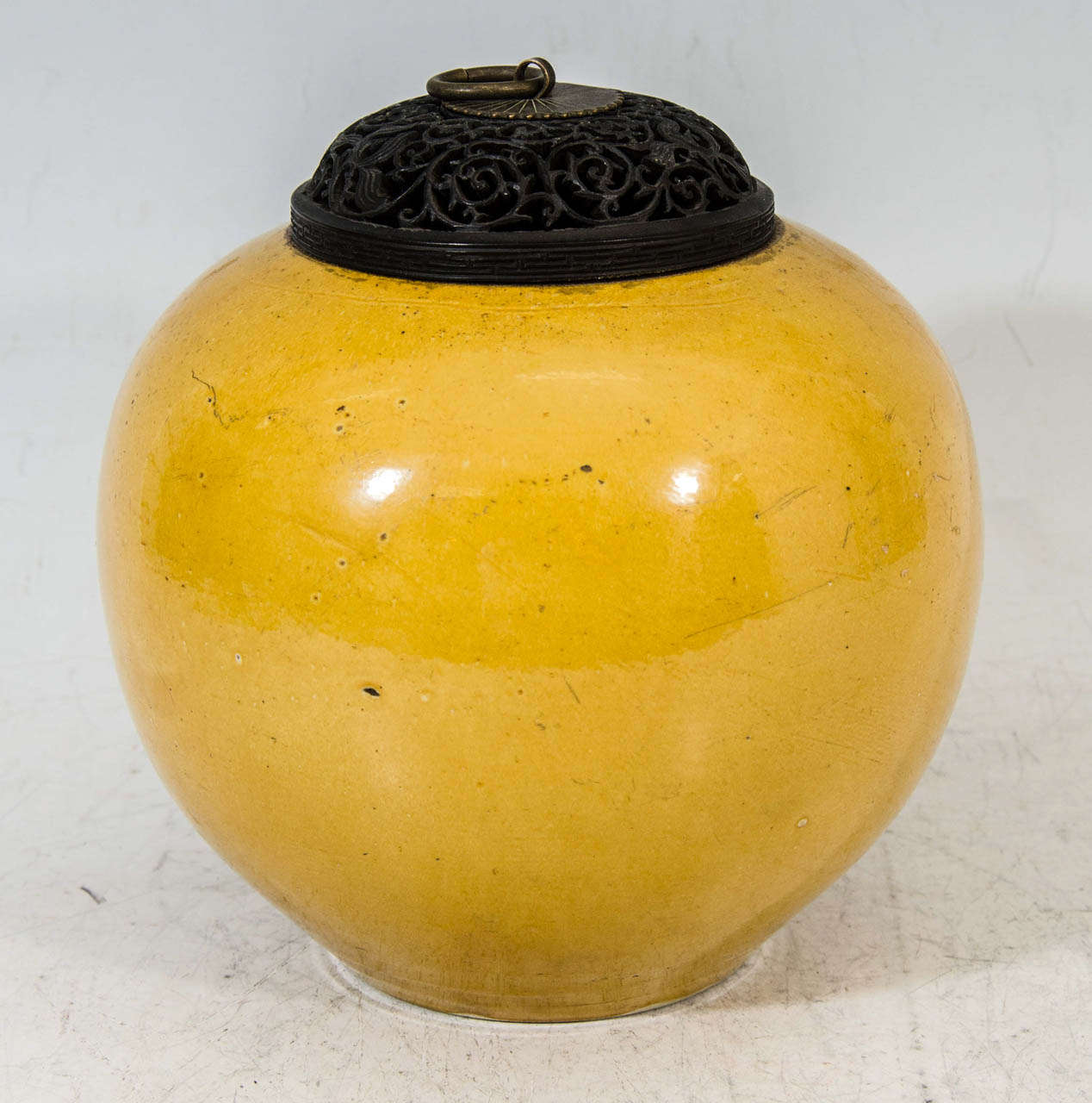 A late 17th or early 18th century Kangxi porcelain tea jar enameled over the sides and base with Imperial Yellow enamel.  The jar has a carved hardwood piecework domed cover with a bronze ring handle

Good condition with age appropriate wear to