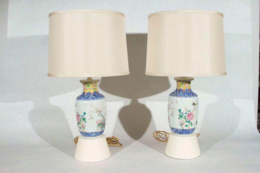 Beautiful pair of Haines table lamps from the estate of F. Hugh Herbert. A pair of delicately hand-painted 19th C. Chinese vases with a bird and flower motif have been mounted on ivory lacquered bases. The silk shades with top diffusers are new.