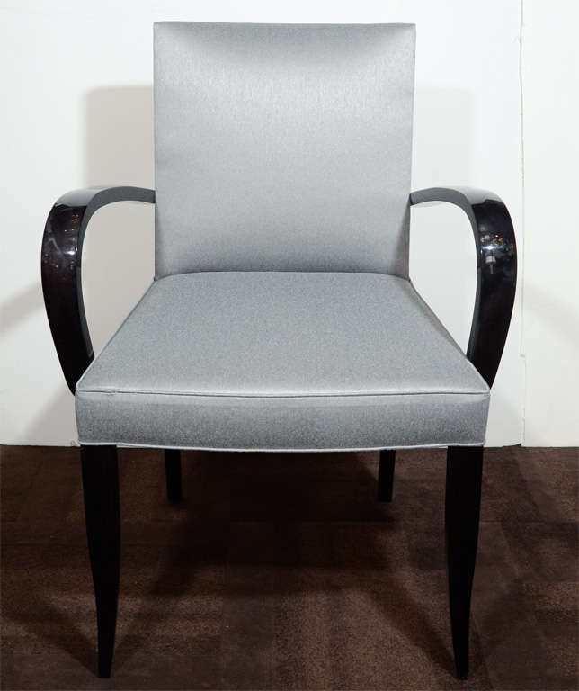 This chair feature a ebonized walnut bentwood arms design with tapered legs. They have been newly reupholstered in a silver sharkskin metallic silk/wool blend fabric. This is a fine example of Mid-Century Modern design with its clean lines and luxe