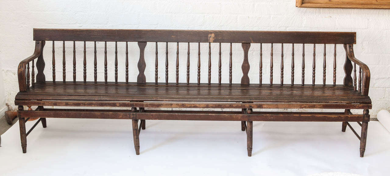 This extremely long bench has a great look with niclely turned back columns,  shaped stretchers, bent wood arms and a slated seat. This piece has the look of country train station bench and would fit well in a variety of residential and commercial