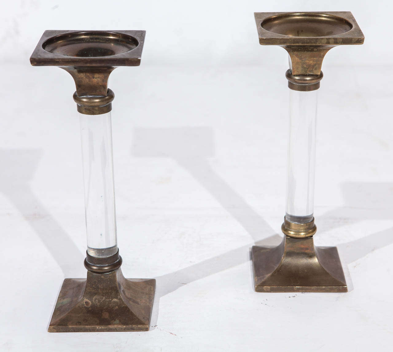 A classical pair of columnar brass and Lucite candlesticks in the manner of Dorothy Draper.