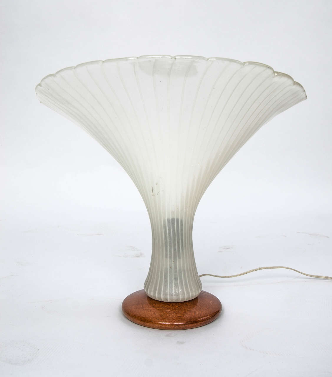 A fan-shaped glass light of Italian Murano glass, attributed to Venini, with delicate zanfirico/merletto patterns, on a wooden base, mid-20th century. 

The lamp is in very good original condition with one small chip on the reverse edge, which is
