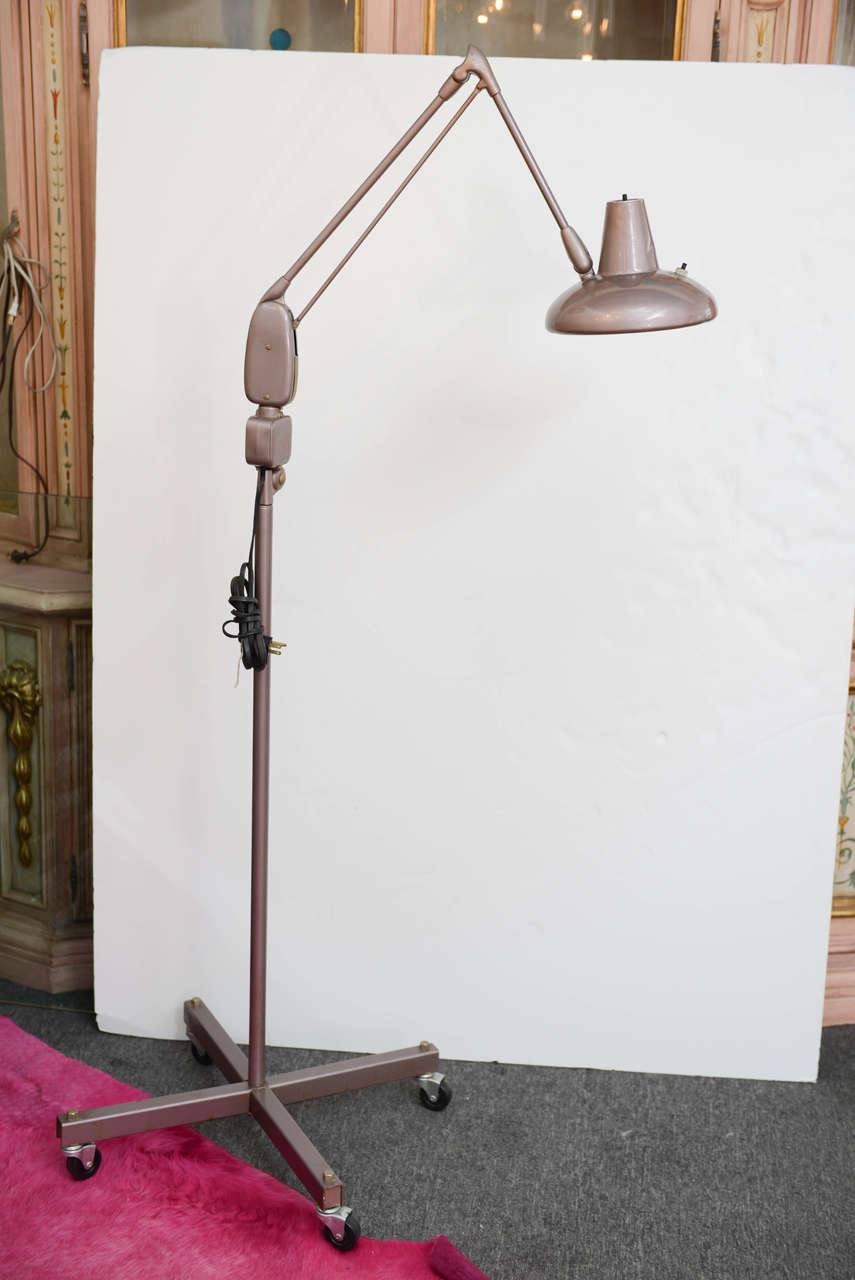 Cast a spotlight on your work with this cool floor lamp.  Made of painted metal, the four casters allow it to be easily moved around an area.  Large hinge midway up the height of the lamp allows the lamp head to focus quite high.  Lamp arm does not