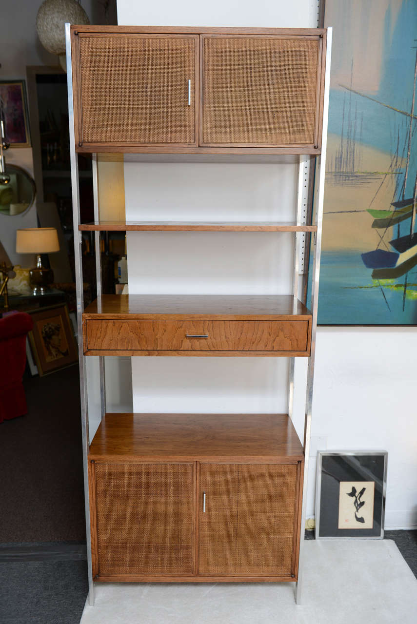 Tall cabinet freestanding mid century Eames era. These kinds of pieces have become increasingly difficult to find.  stainless steel supports hold 2 storage units, one drawer and one shelf.  Woven door fronts and magnetic door closures.  Interesting