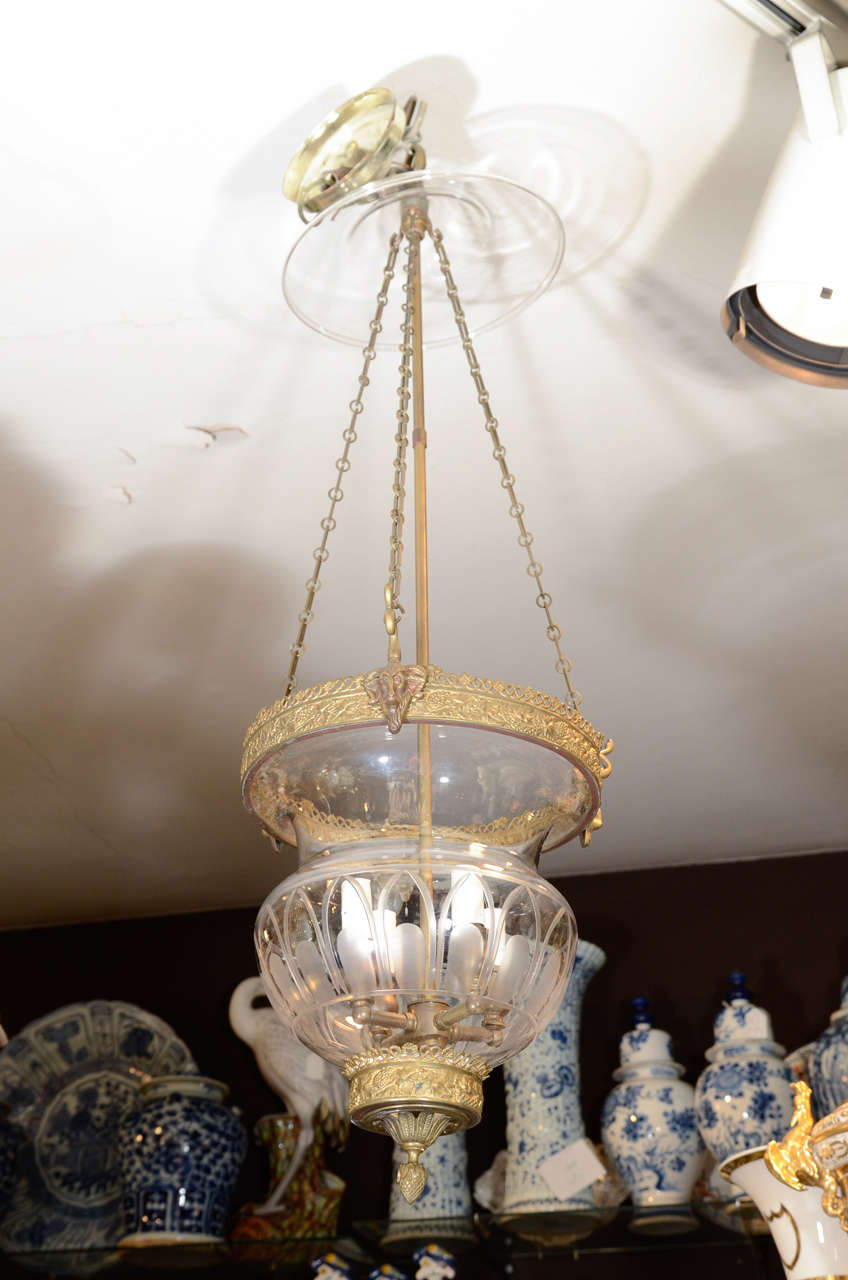 An English glass pendant lantern with etched arcades, completed by a smoke cap.
The metal bands have impressed neoclassical designs of grape vines, acanthus leaves, satyr heads and a pineapple finial.